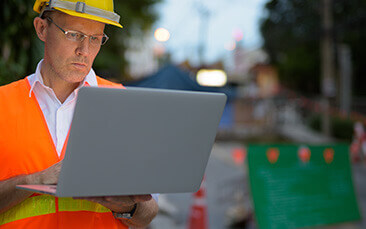 Man with a hard hat and laptop. Site Management
